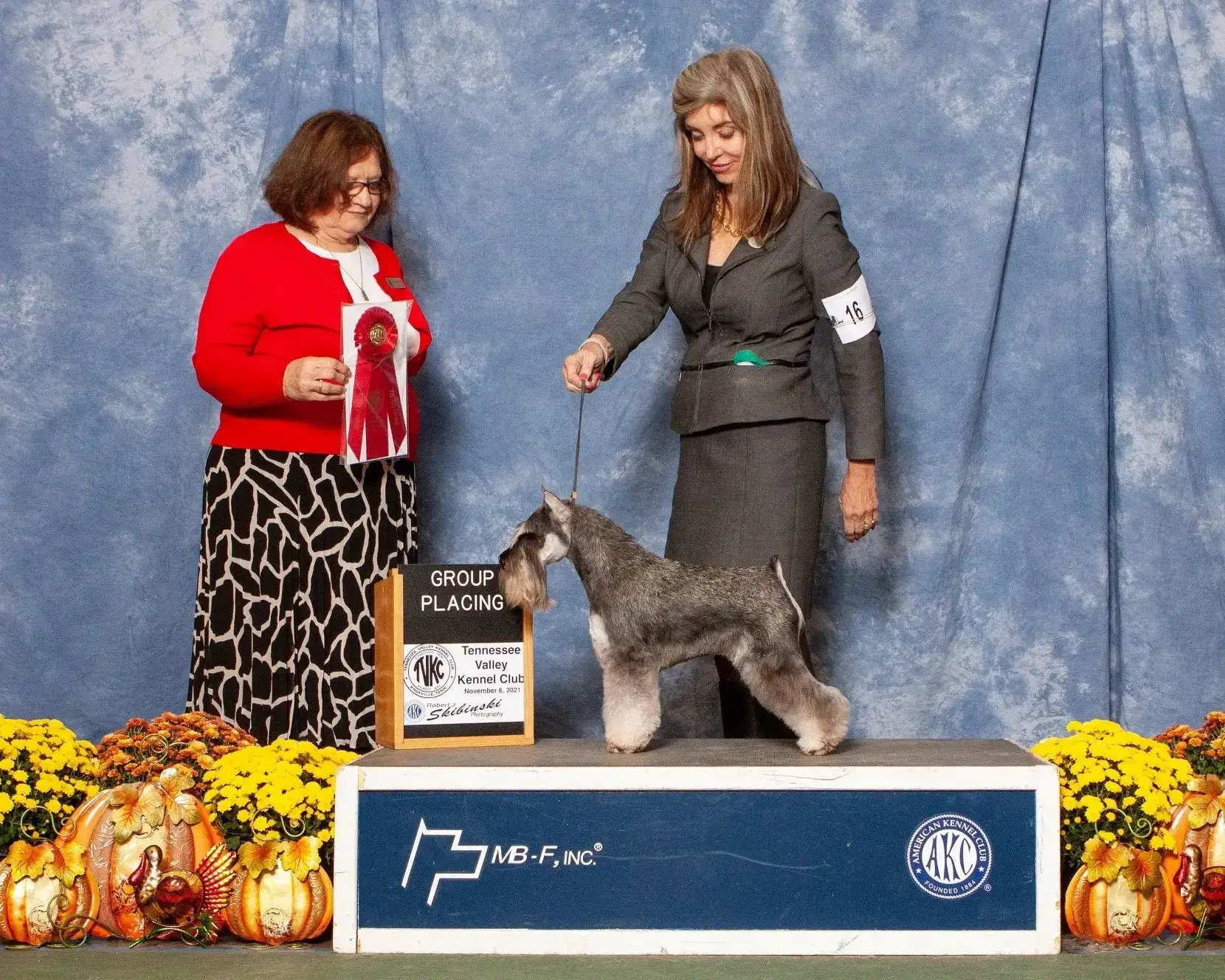 Dog show winners with Schnauzer and ribbon.